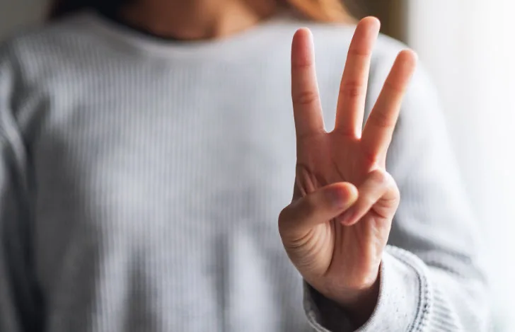 3本の指を立てた女性の手元