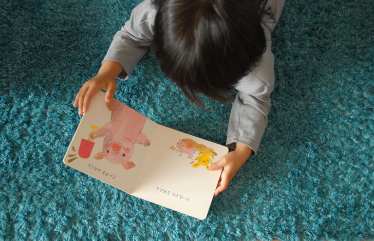 絨毯の上で絵本を読む子供